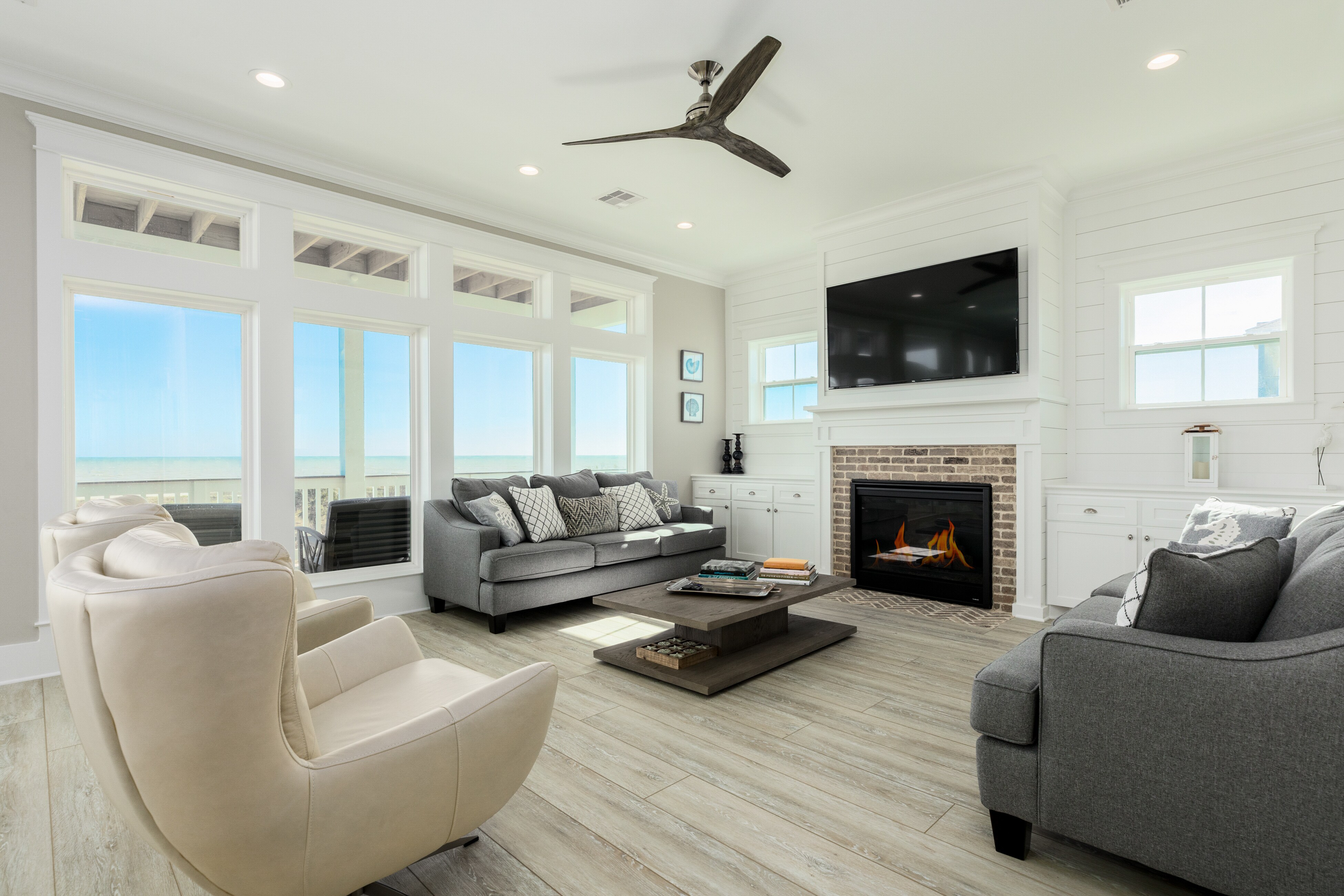 The window-lined living room features a gas fireplace and a 65" TV.