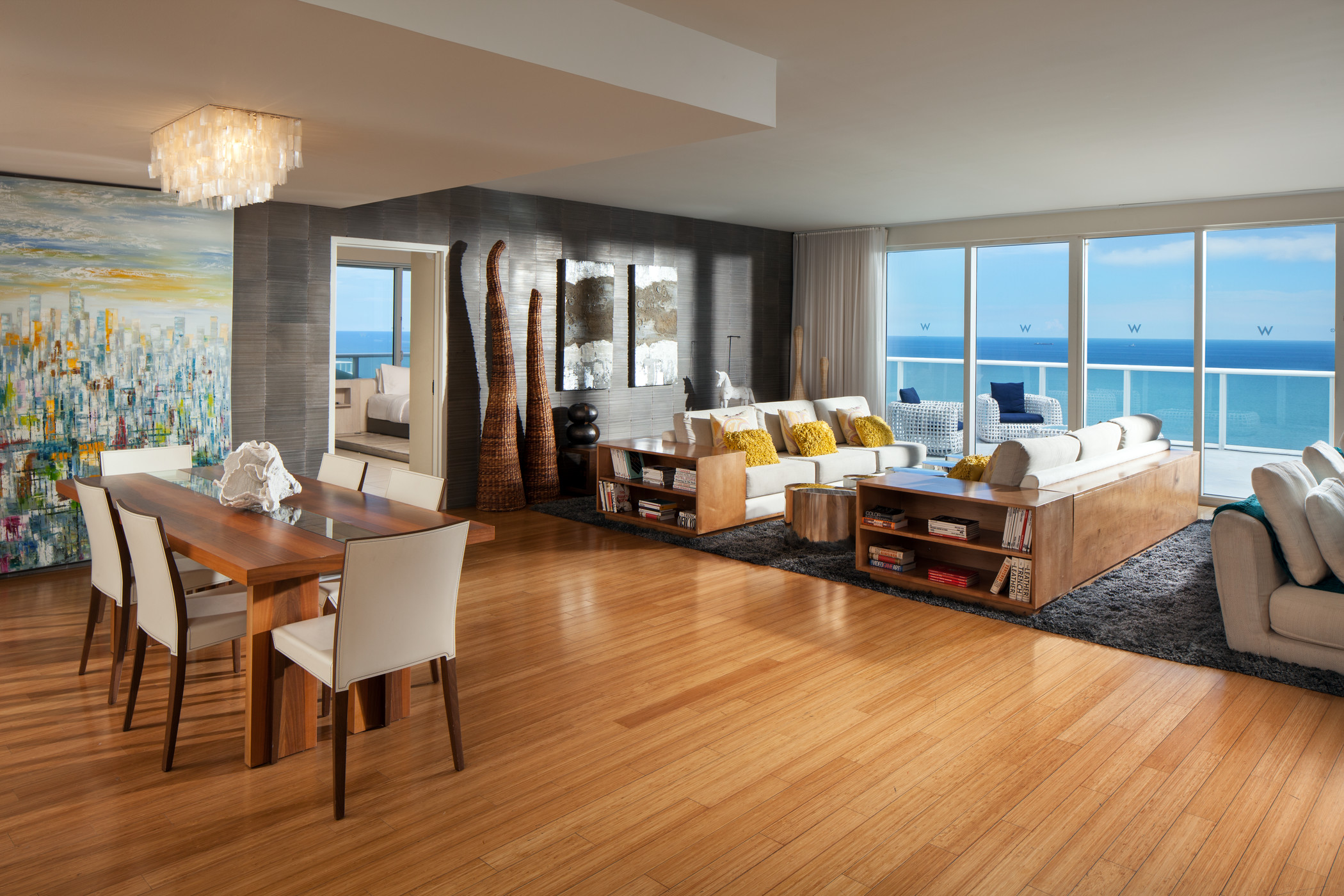 Living room and dining area with large mural and balconyl with ocean view