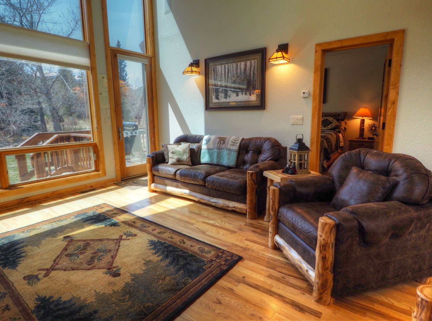 Rambling River Condo - Living area with door to outside deck and entry to master suite