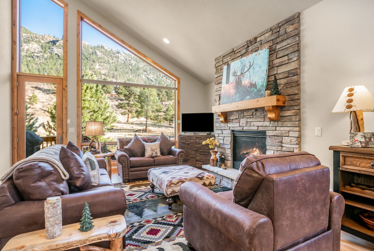 River Rock Retreat - Main floor living room with ample sofa seating, gas fireplace, and a serene view out to the deck. Townhome is adorned with charming mountain decor.
