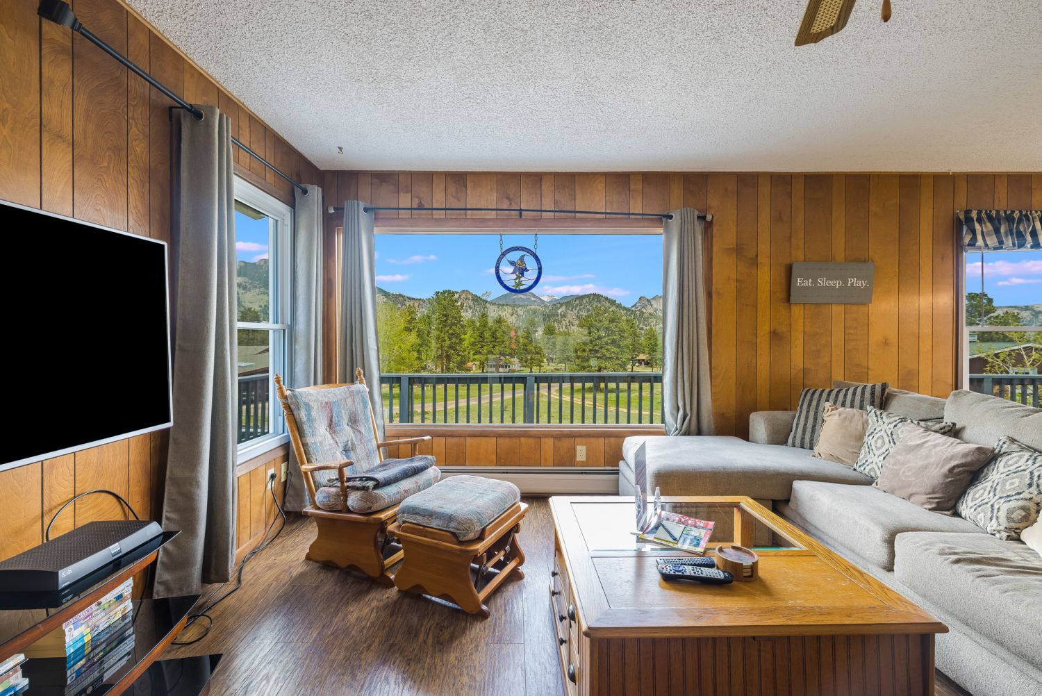 Grandma's Mountain Getaway - Living room with a sectional couch, rocking chair and ottoman, flat screen TV and a large window with beautiful mountain views