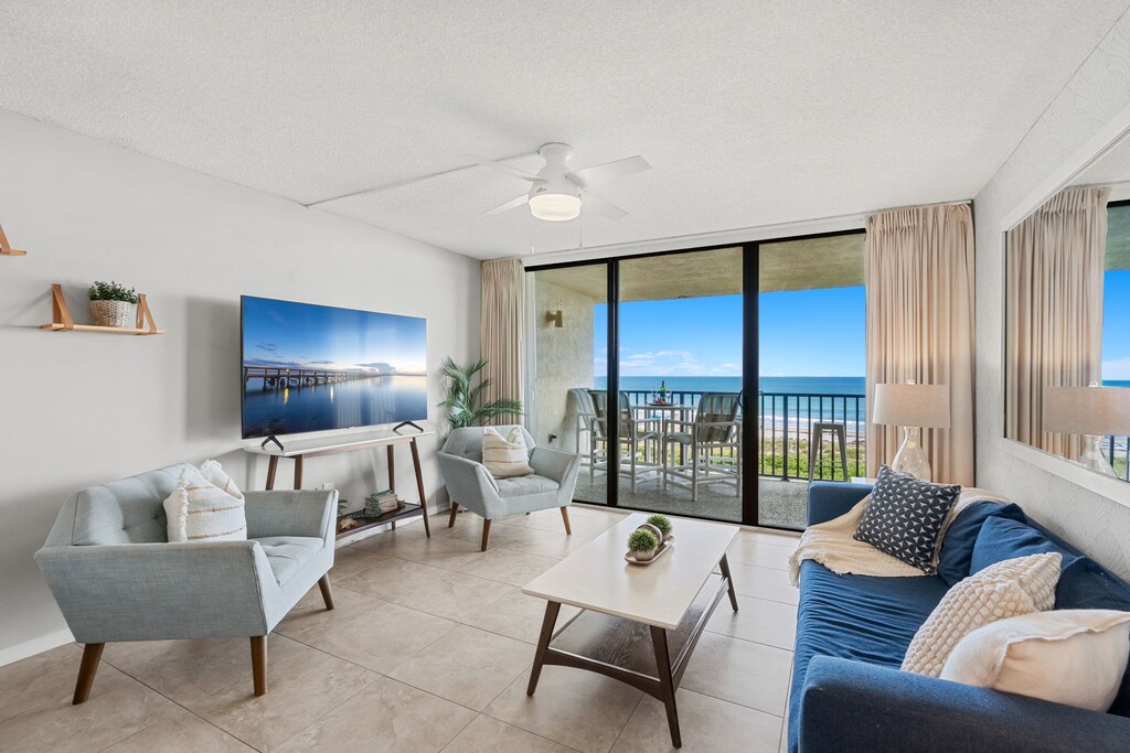 Bright & airy living room with sliding glass doors that lead to oceanfront balcony