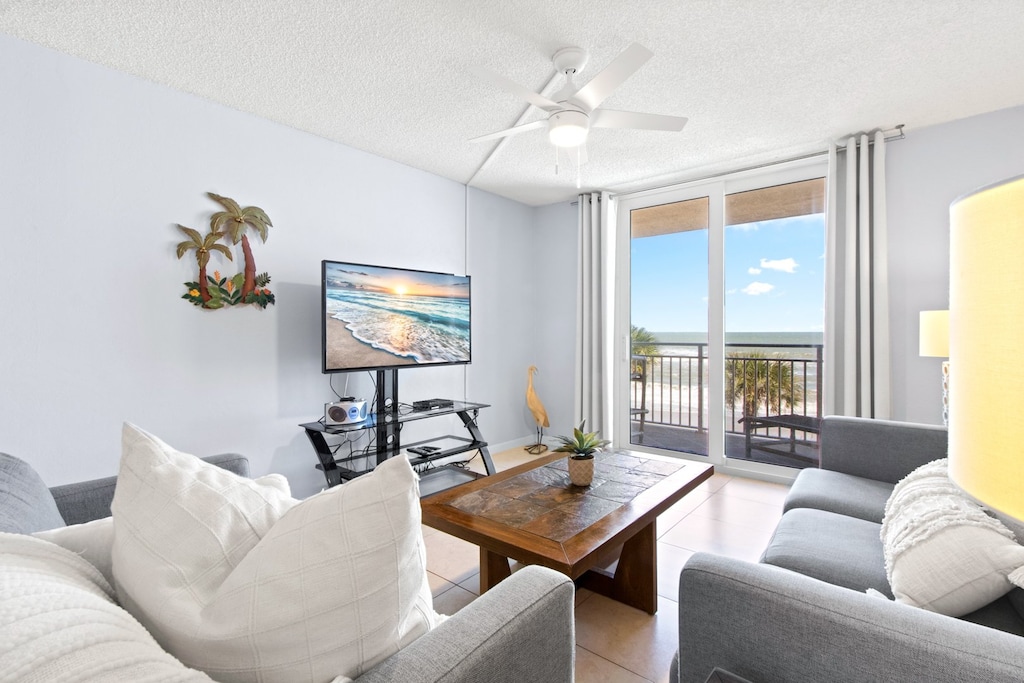 Bright and inviting living room with a plush sectional sofa, wooden coffee table, and a stunning oceanfront balcony view.