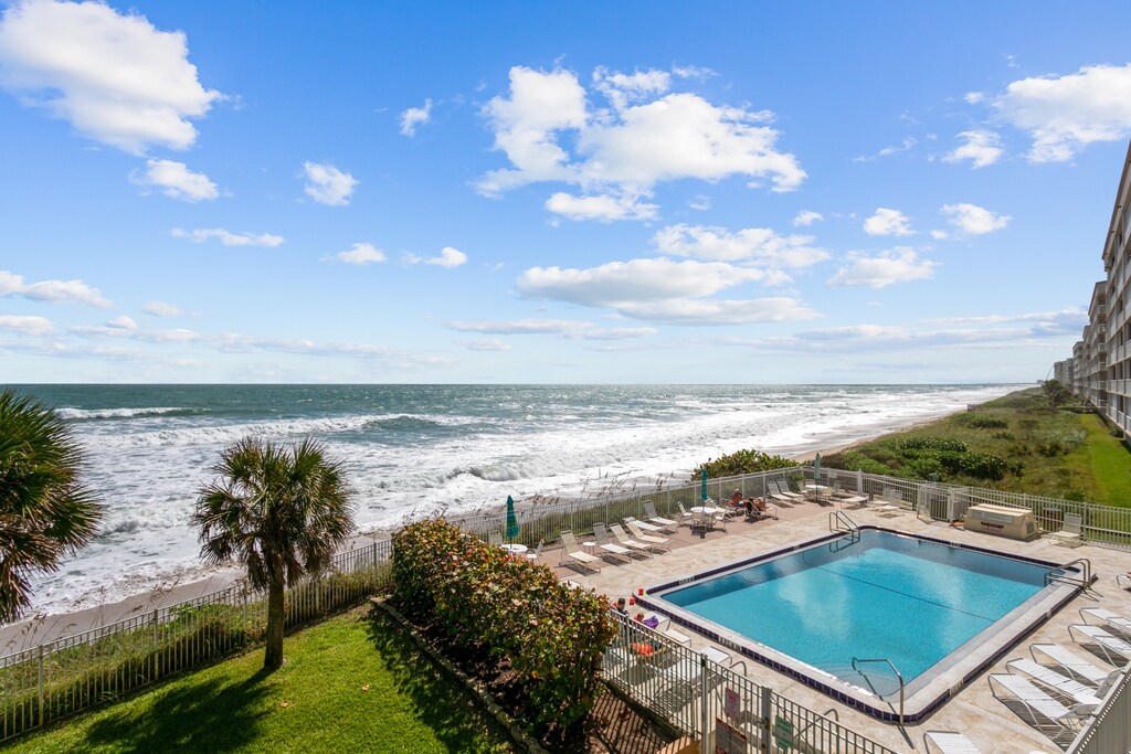 Scenic pool area overlooking the ocean, surrounded by lounge chairs.