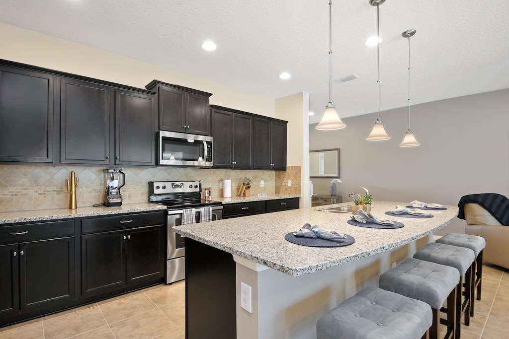Outstanding modern style kitchen with microwave, stove, oven, and barstool seating