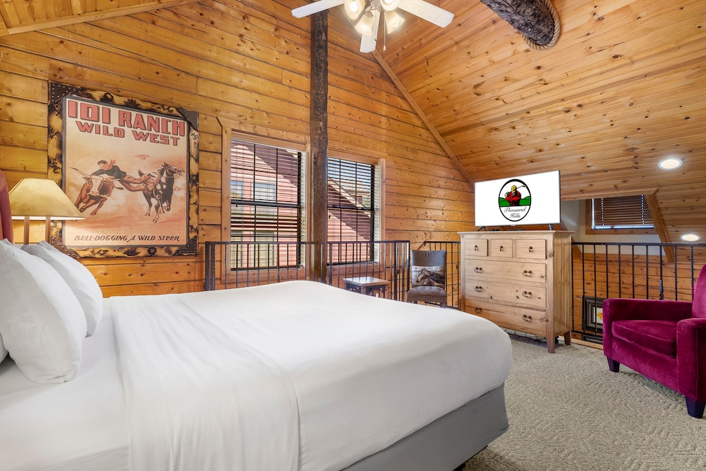 Cozy up in the charming open loft bedroom, featuring vaulted wood ceilings, rustic décor, and a private TV for a relaxed retreat.