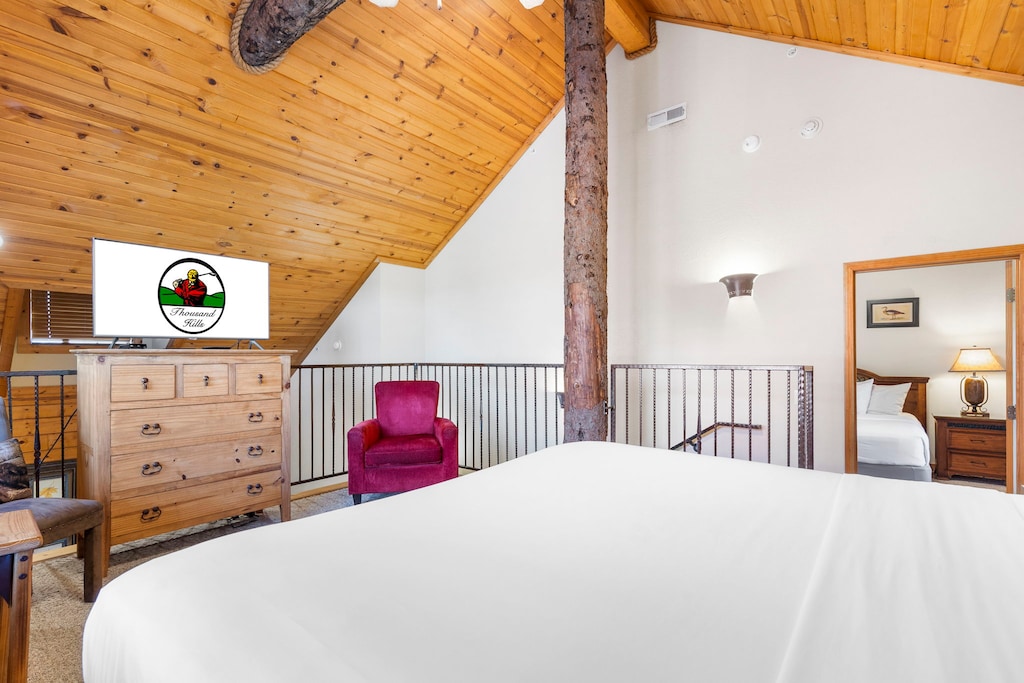 Rustic loft bedroom with vaulted ceilings, cozy charm, and a private TV.