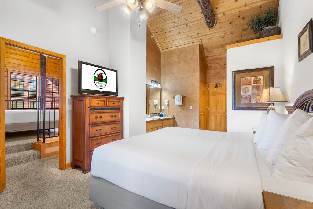 Spacious bedroom with vaulted ceilings, a private TV, and direct access to the loft and an ensuite bath