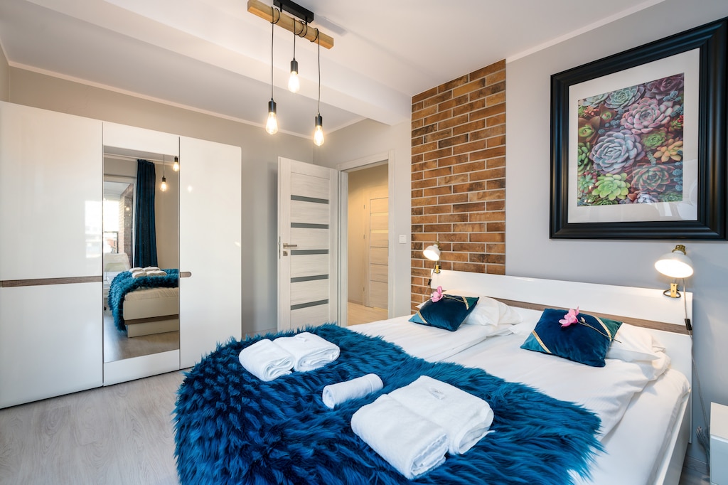 Bedroom of Niedziałkowskiego 10/10 with double bed, wardrobe, bedside lamps and mirror