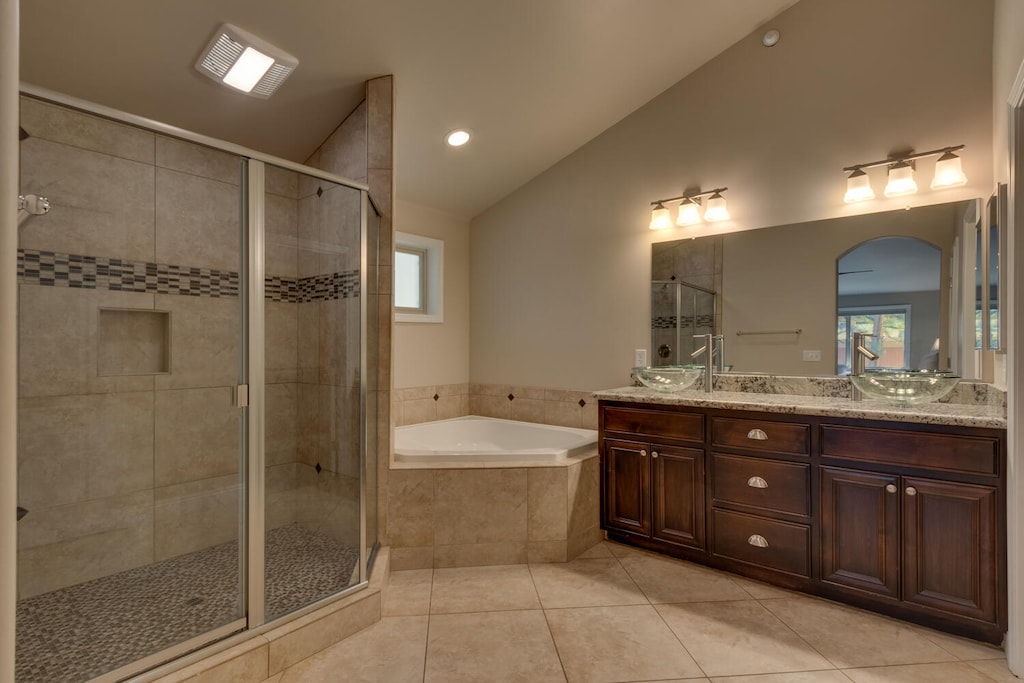 Bathroom with jetted tub, glass-enclosed shower, and dual sinks