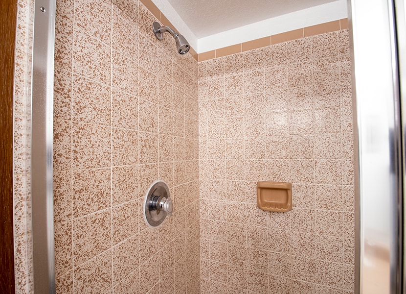 Step into your private sanctuary with this spacious tiled shower featuring elegant speckled stone walls and modern fixtures for a refreshing start to your day.