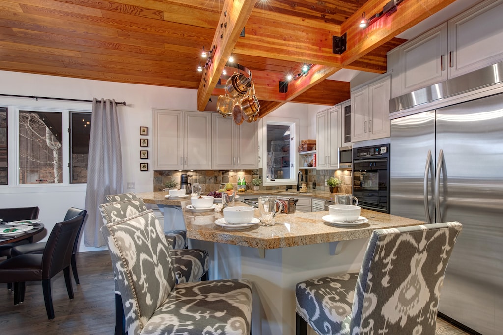 Fully Equipped Kitchen with stainless steel appliances, stone countertops, wine fridge, and bar seating for 4