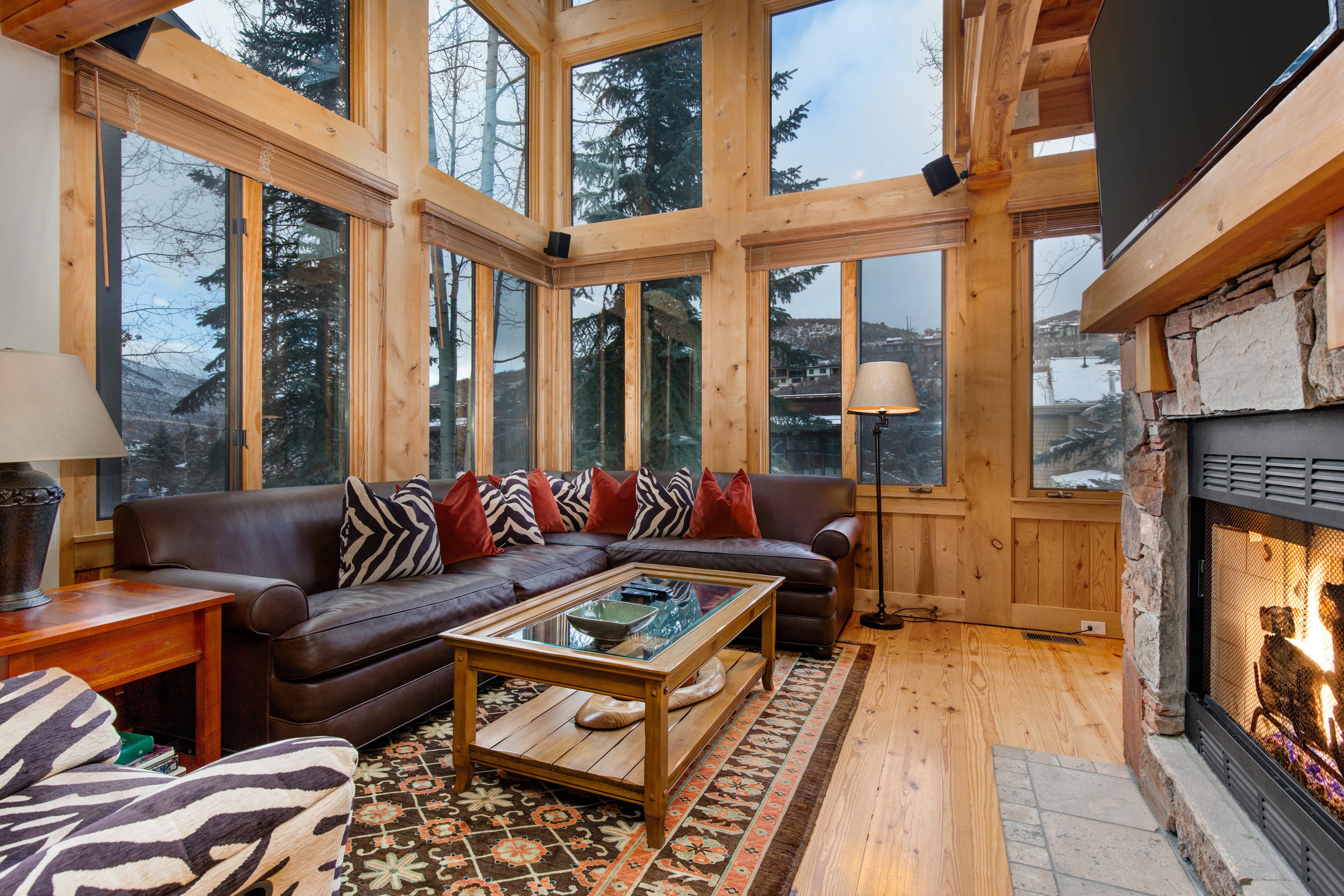 Living Room with vaulted ceilings, stunning windows that allow for an abundance of natural light, leather furnishings, full sofa-bed, gas fireplace, and 55" Vizio TV