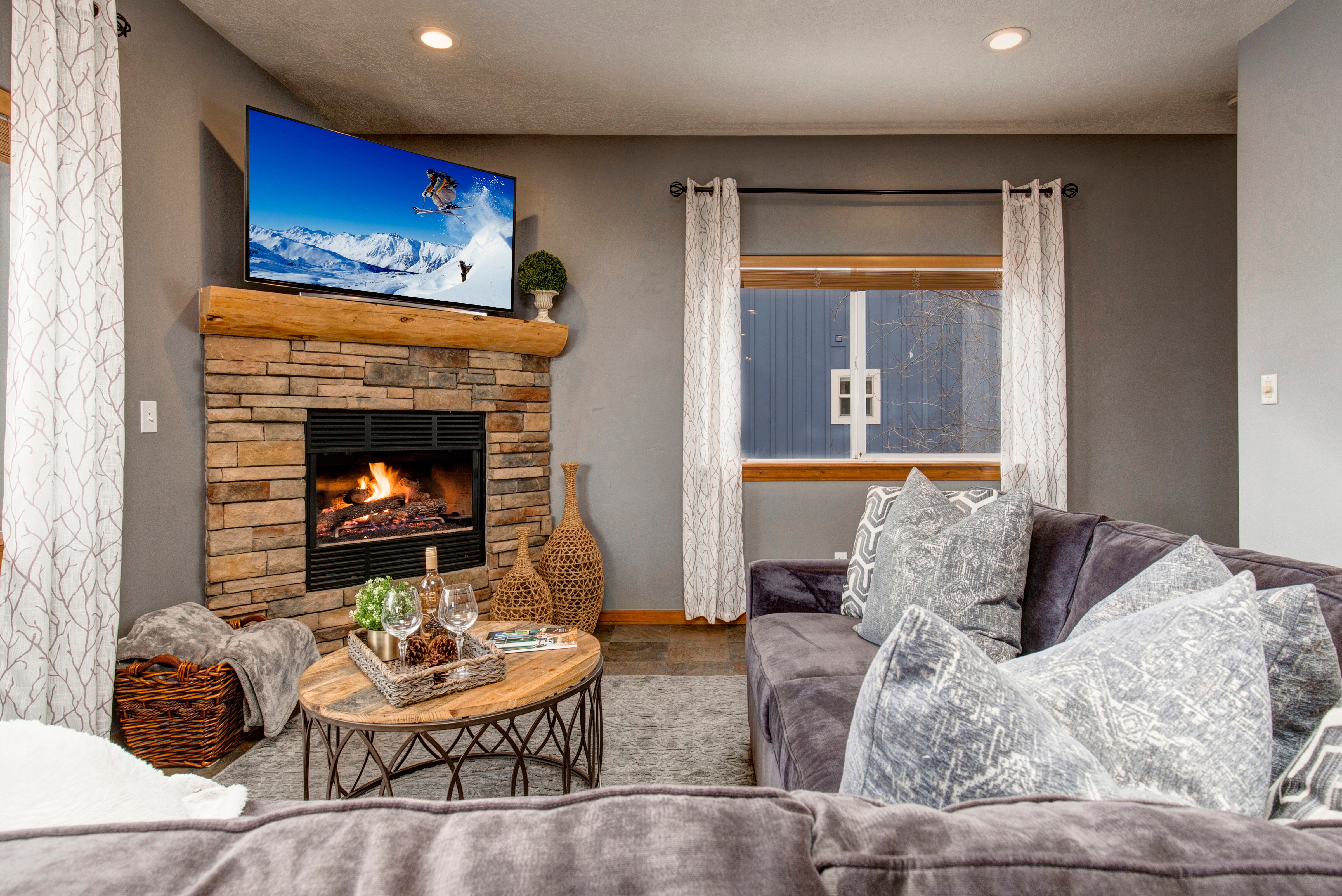 Main Level Living Room with plush sectional, 65" Samsung smart tv, gas fireplace and private deck access