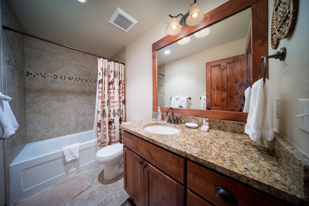 Step into your beautifully appointed bathroom featuring granite counters, rustic wood vanity, and a relaxing tub-shower combo.