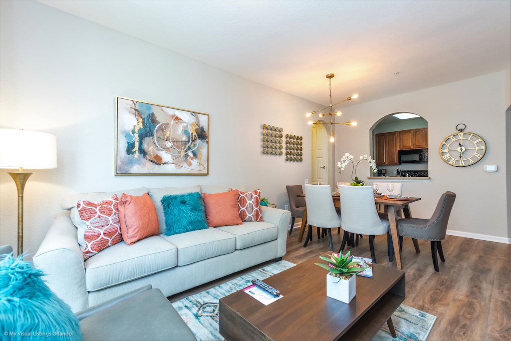 Next to the dining room is the  vibrant living room featuring a cozy sofa adorned with colorful throw pillows, adding a lively touch to the space.