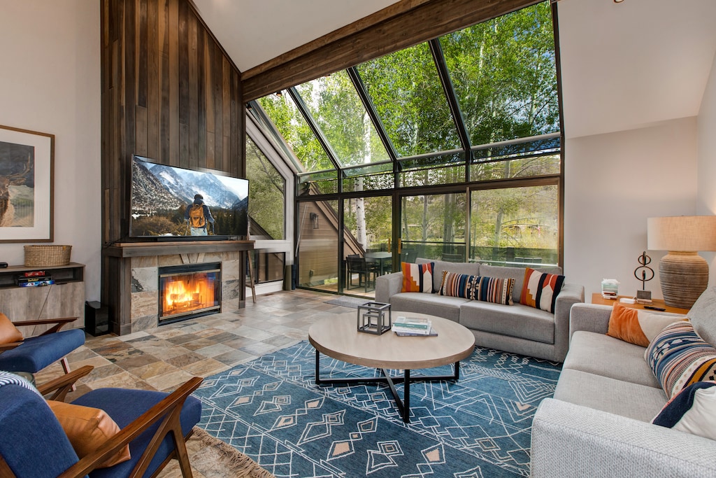 Main Level Living Room with floor to ceiling windows, gas fireplace, plush furnishings with sofa sleeper, 75" Samsung smart tv, and breathtaking views of Deer Valley