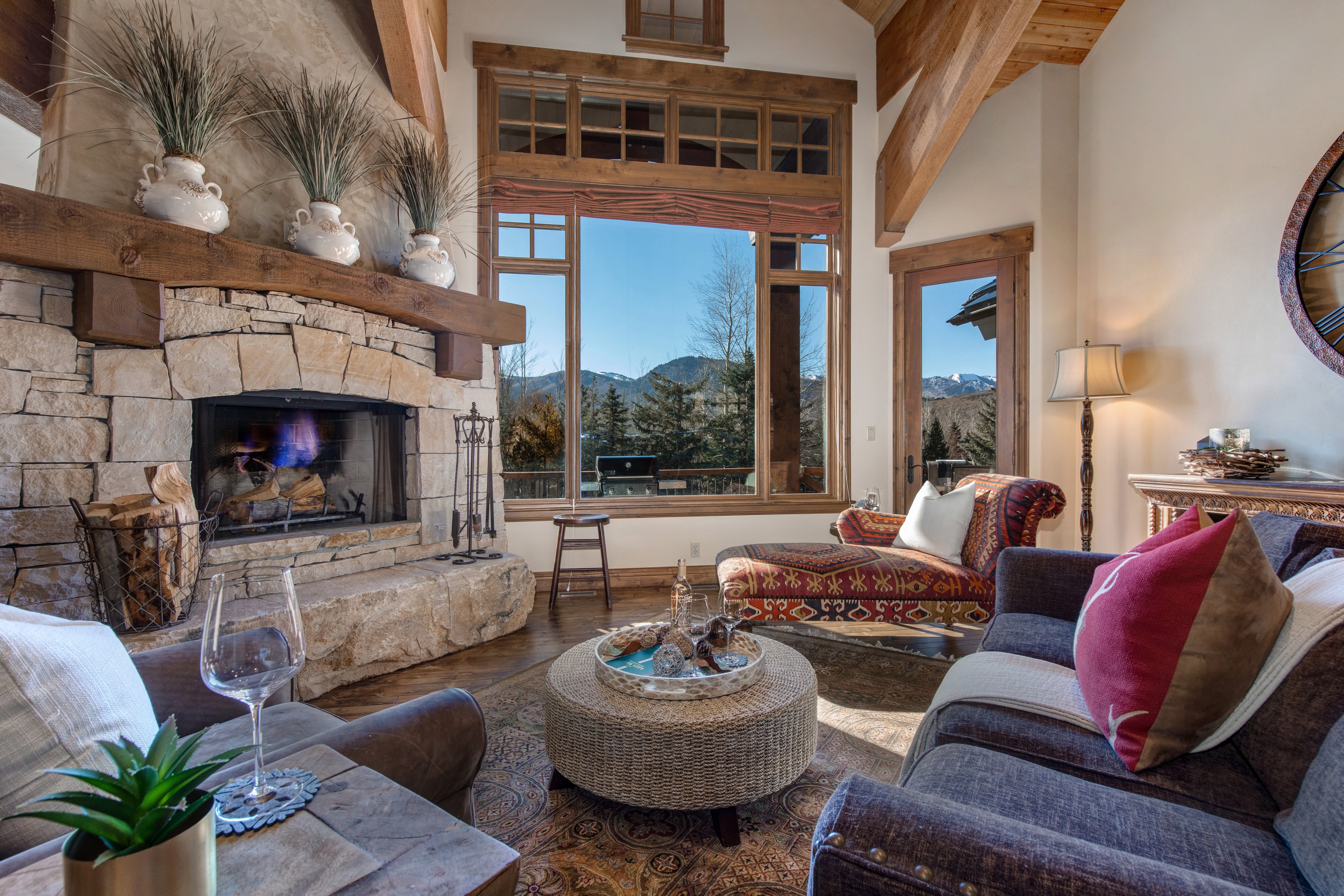 Main Level Living Room with vaulted ceilings, gas-assist fireplace, plush furnishings, wet bar access, and stunning views of the surrounding mountains