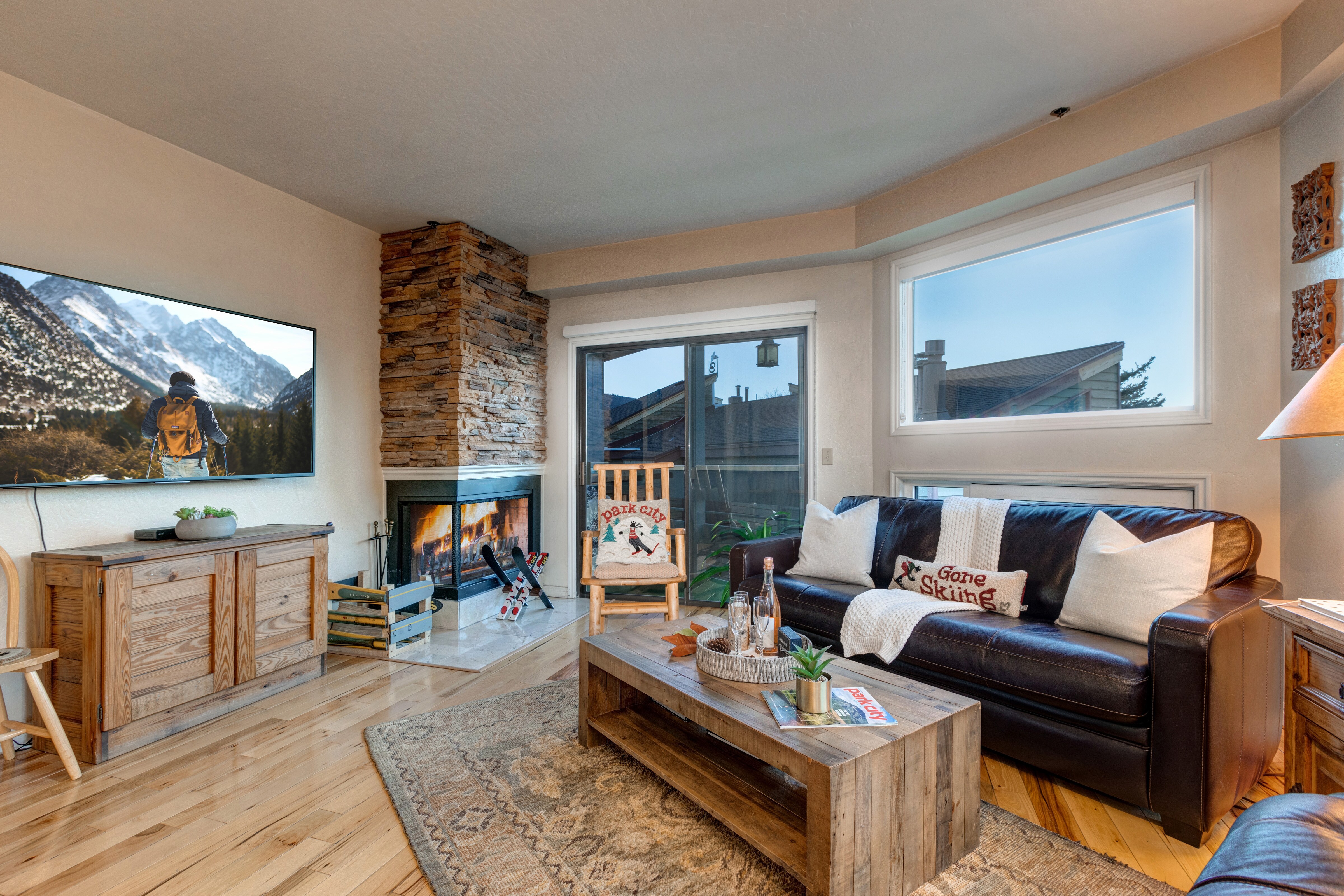 Living Room with 65" Sony Smart TV, wood-burning fireplace, plush leather furnishings, and private balcony access overlooking Park Ave.