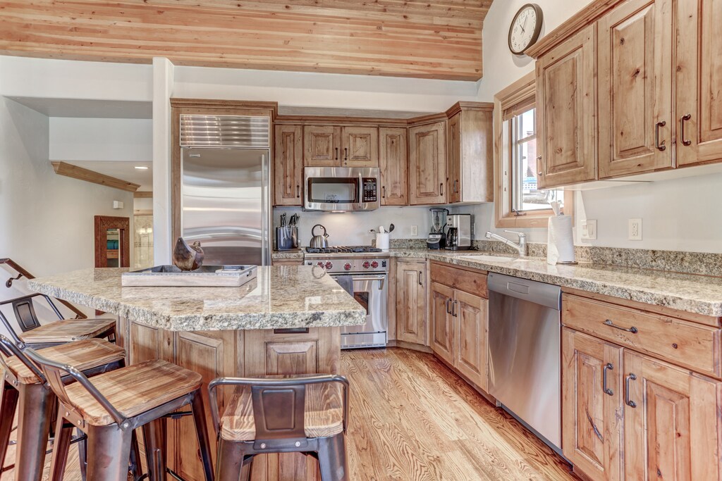 Gourmet display kitchen with Viking refrigerator, 5-burner gas stove, granite counters, and island with 4-bar seats