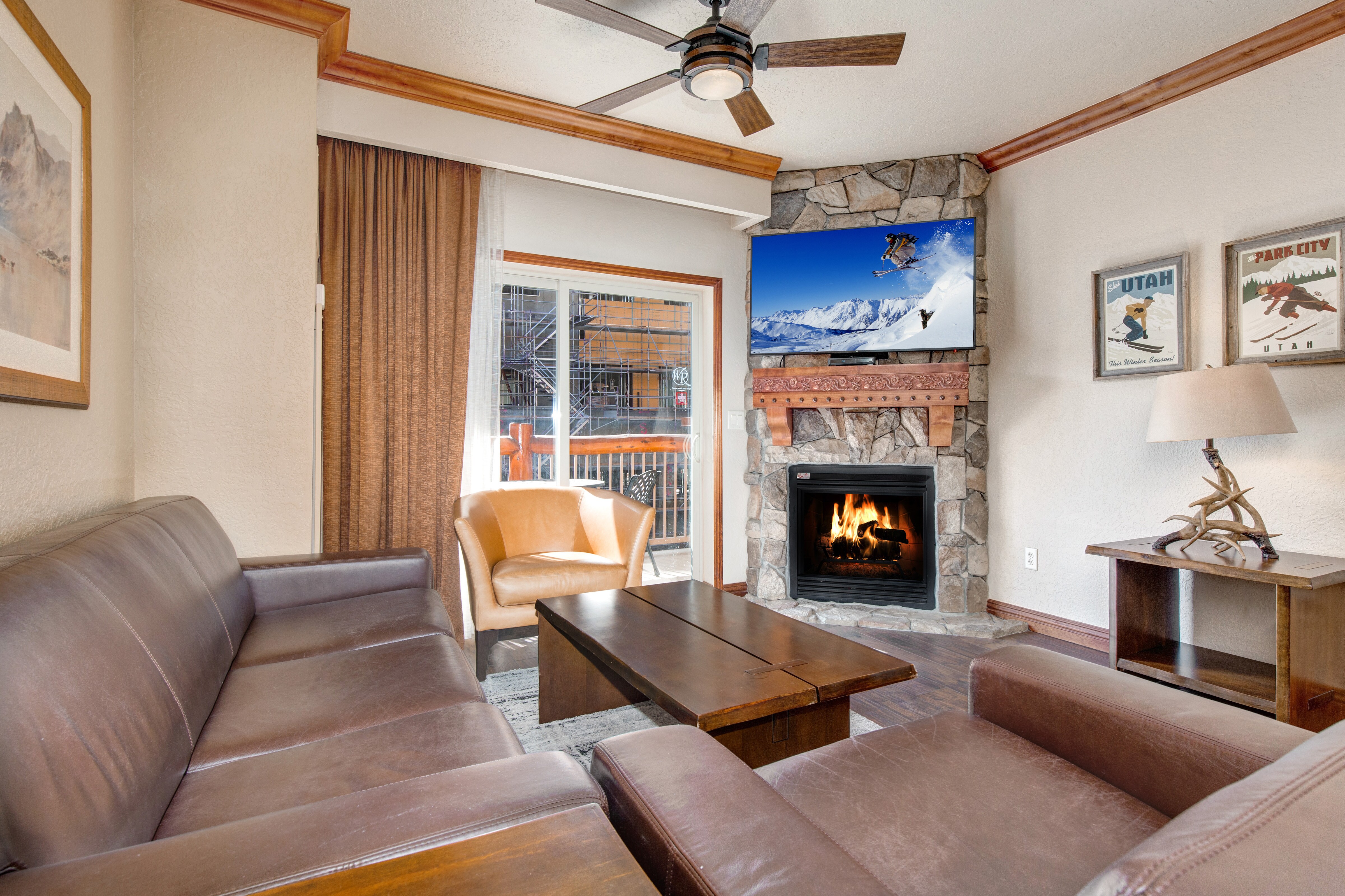 Living Room with gas fireplace, leather furnishings, 55" TV, sofa bed, and private balcony access