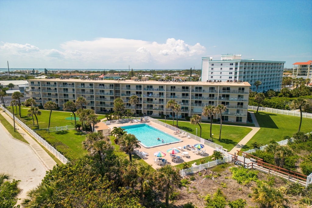 Aerial view of Cocoa Beach Towers with a resort-style pool and lush landscaping.