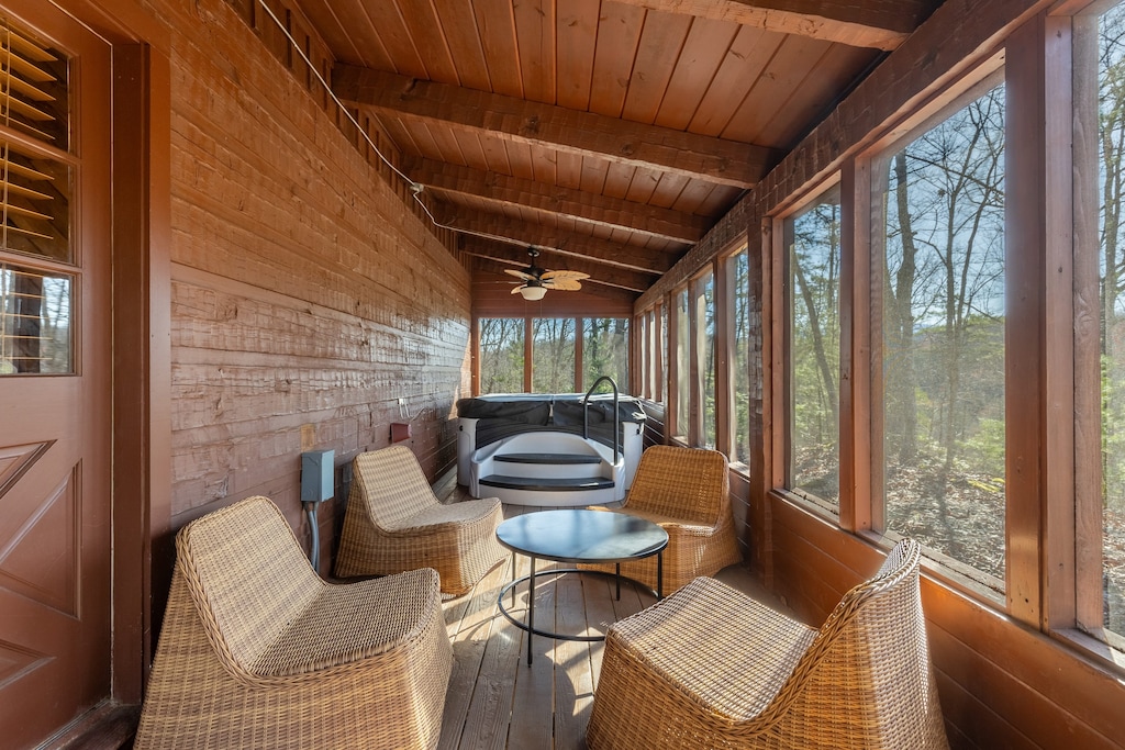 Screened in porch features seating and a hot tub.