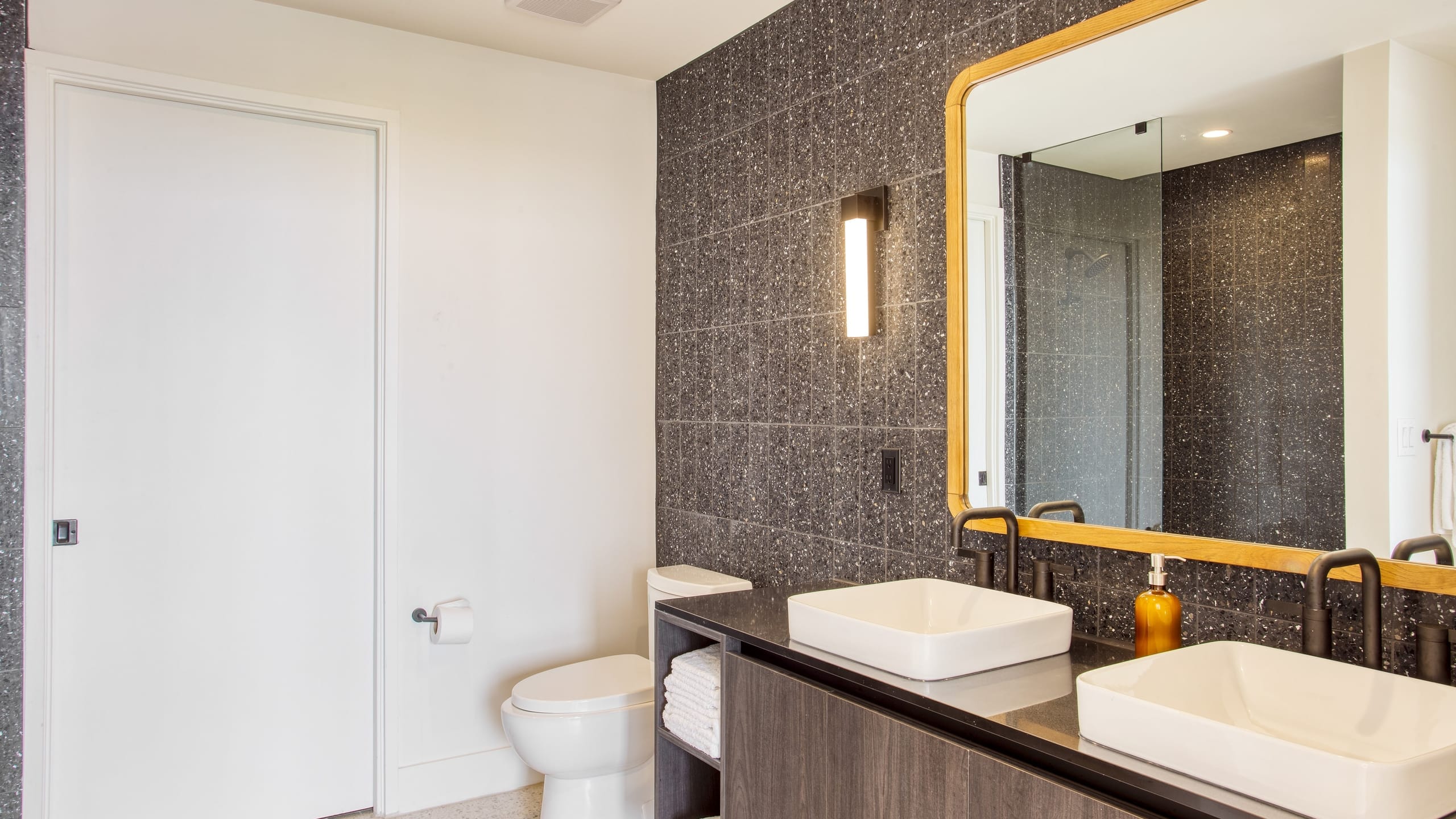 Sleek bathroom with walk-in shower, double vanity, and large mirror.