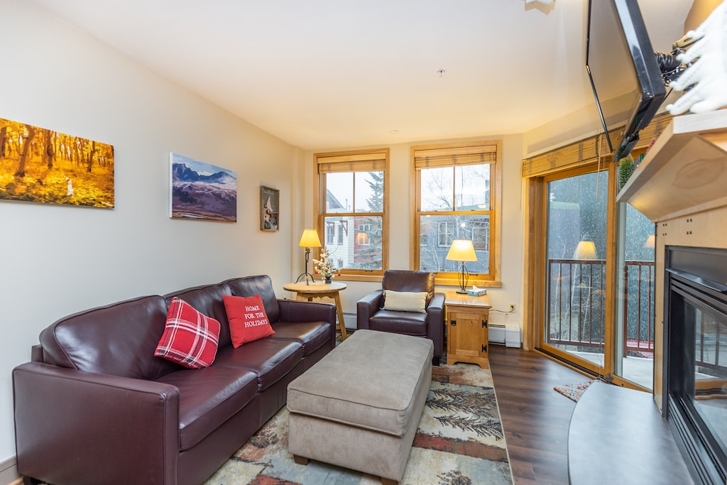 Living area with mounted flat screen TV, gas fireplace and ample seating. 