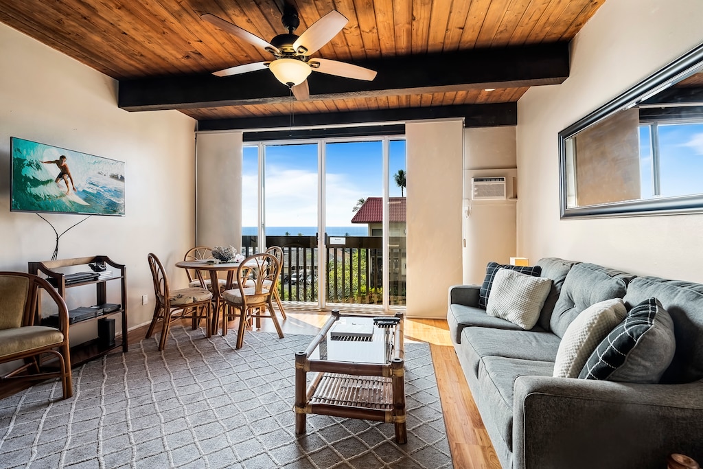 Bright living room with A/C, sleeper sofa, and ocean backdrop.