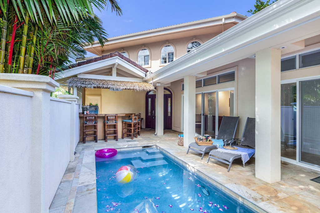 Tropical courtyard with poolside seating and tiki bar for ultimate outdoor relaxation.