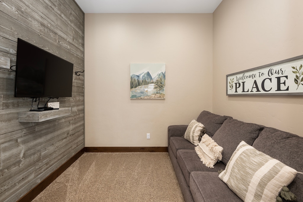 Settle into your cozy living room with rustic wood accent wall, comfy sofa, and modern TV for relaxing evenings.