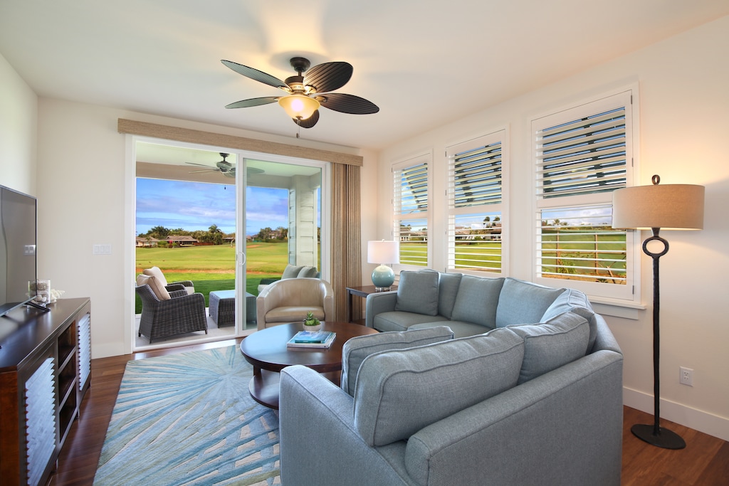 Relax in the open-concept living room, featuring a plush sectional and serene golf course and ocean vistas.