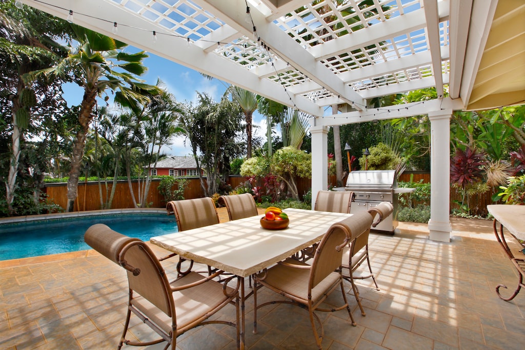 Dine al fresco under the charming pergola in this tropical setting.