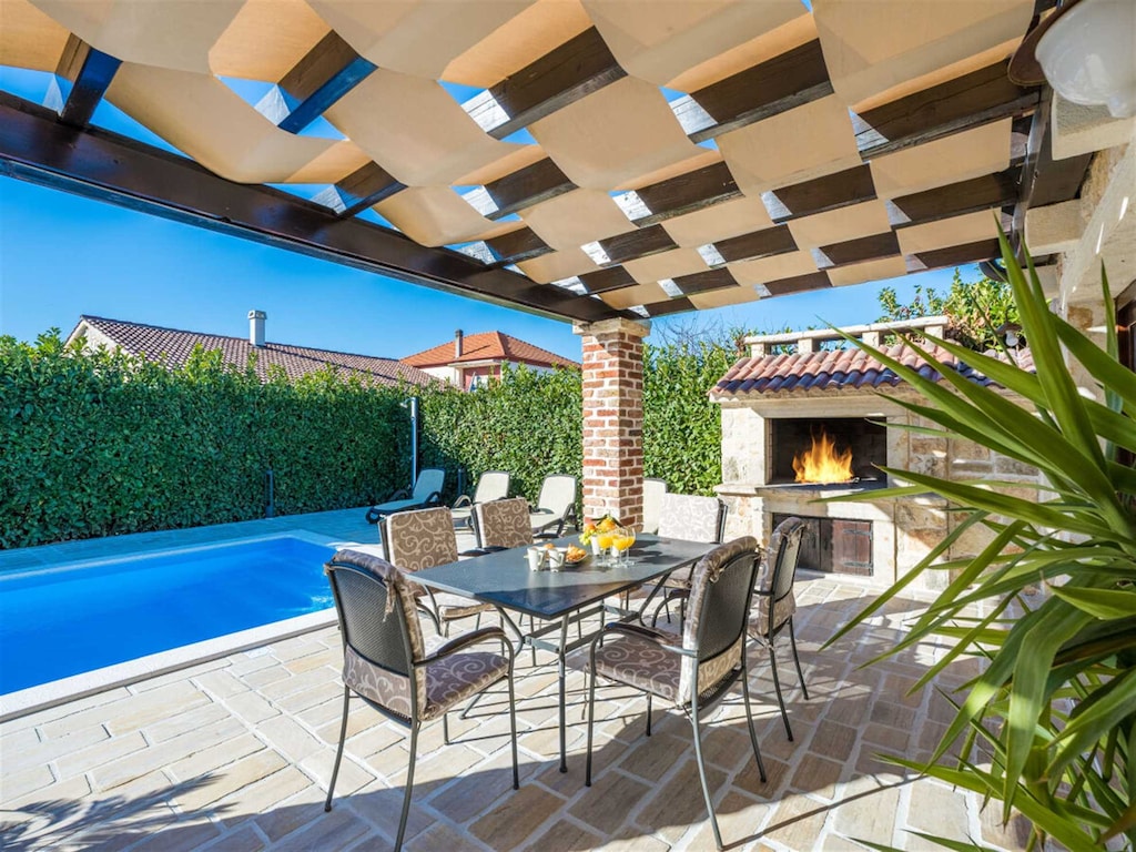 Terrace with outdoor fire place and a swimming pool
