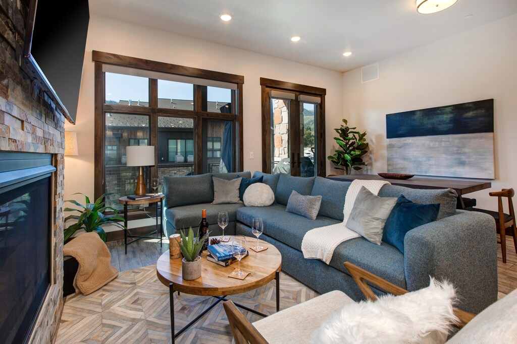 Living Room with plush sectional and arm chair, 65" smart TV, gas fireplace, and private deck access