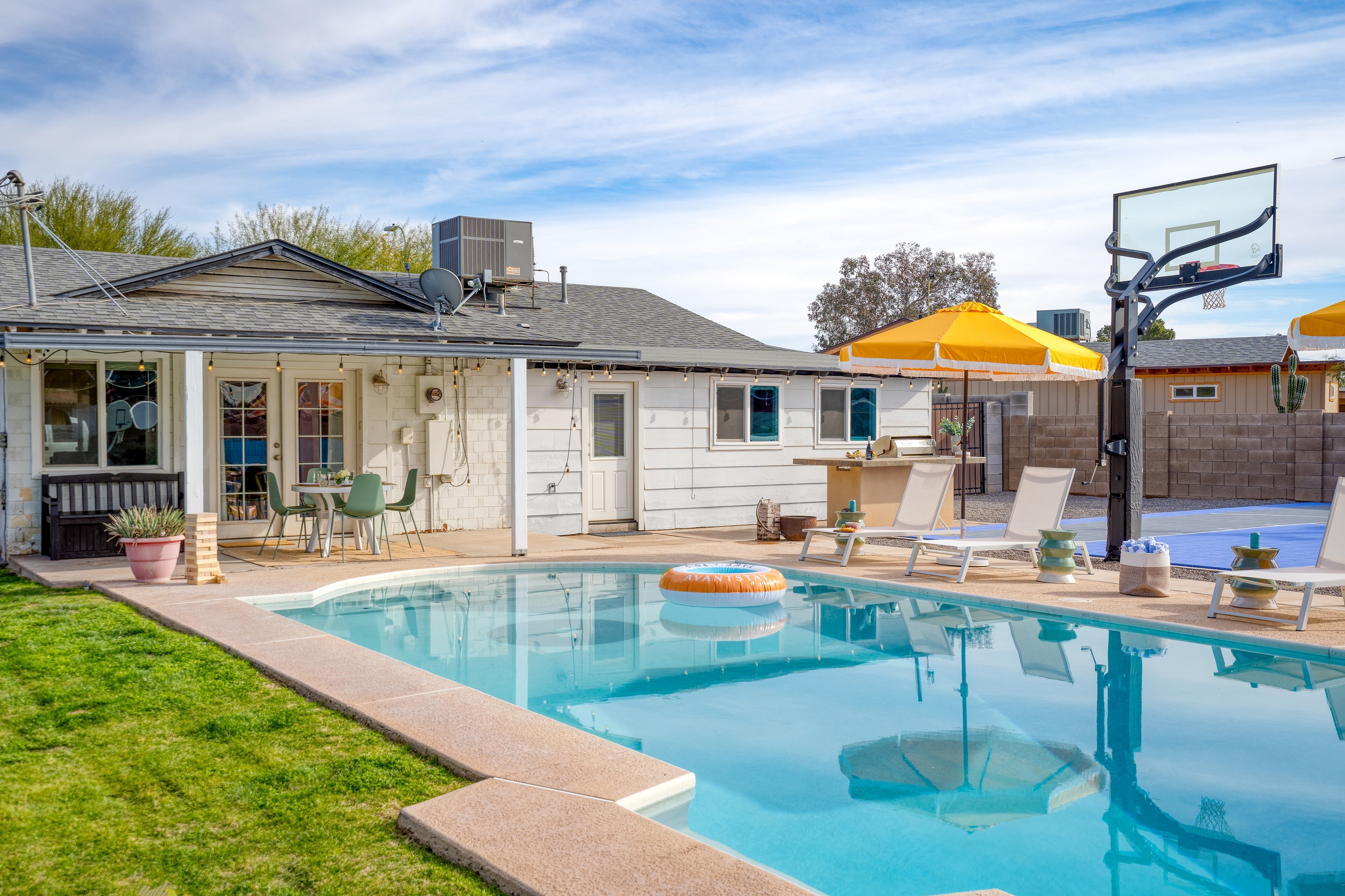 Entertainer's backyard with a pool, basketball court, firepit, and dining area.