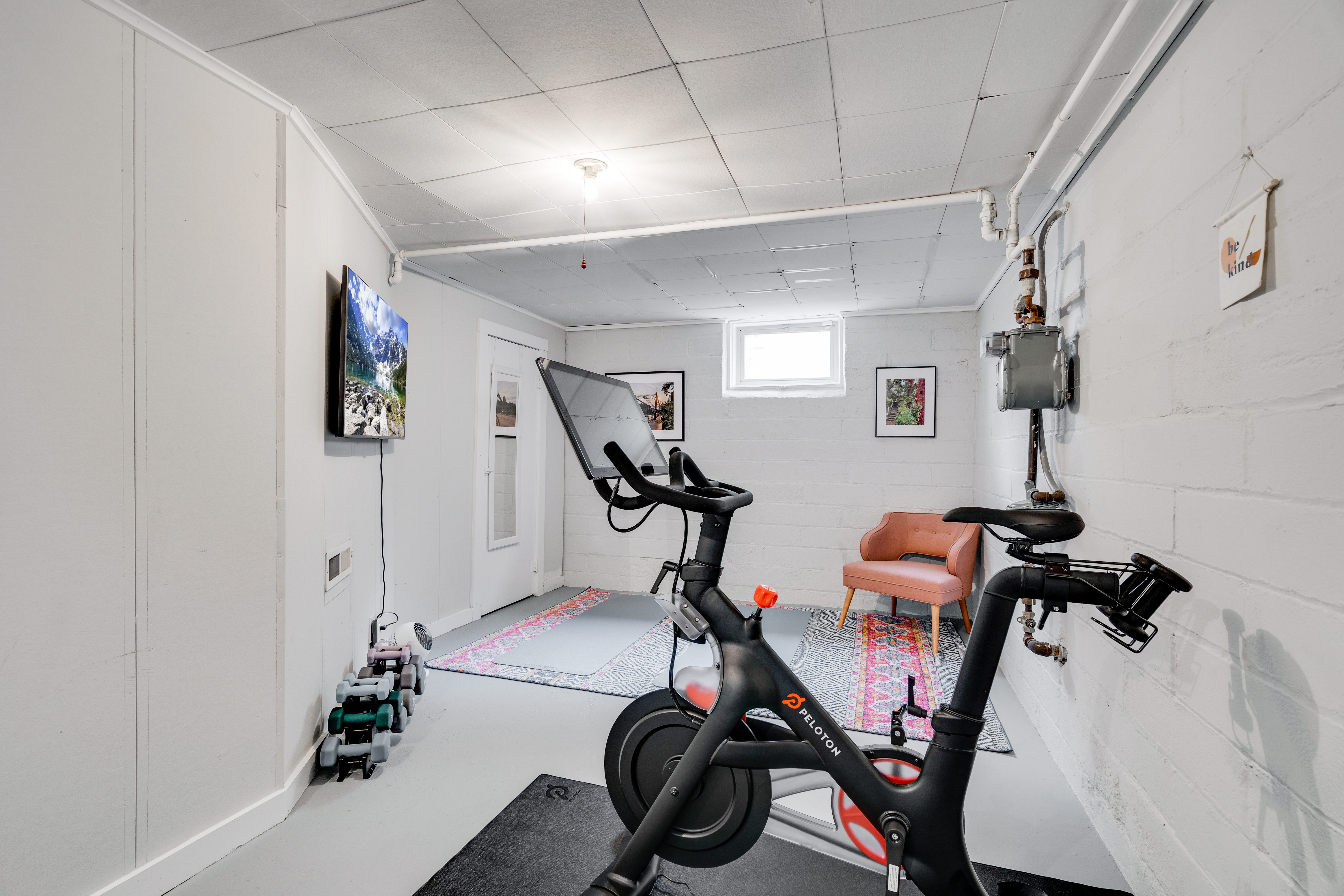 Personal workout space with Peloton Bike, free weights, yoga mat, and Samsung TV