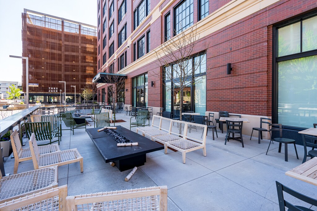 Modern urban patio with contemporary seating and fire features surrounded by stylish brick architecture in a vibrant city setting.