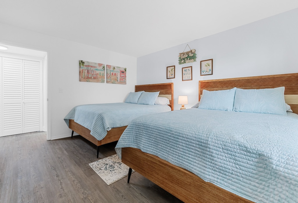 Spacious guest bedroom with two cozy queen beds and soft blue decor.