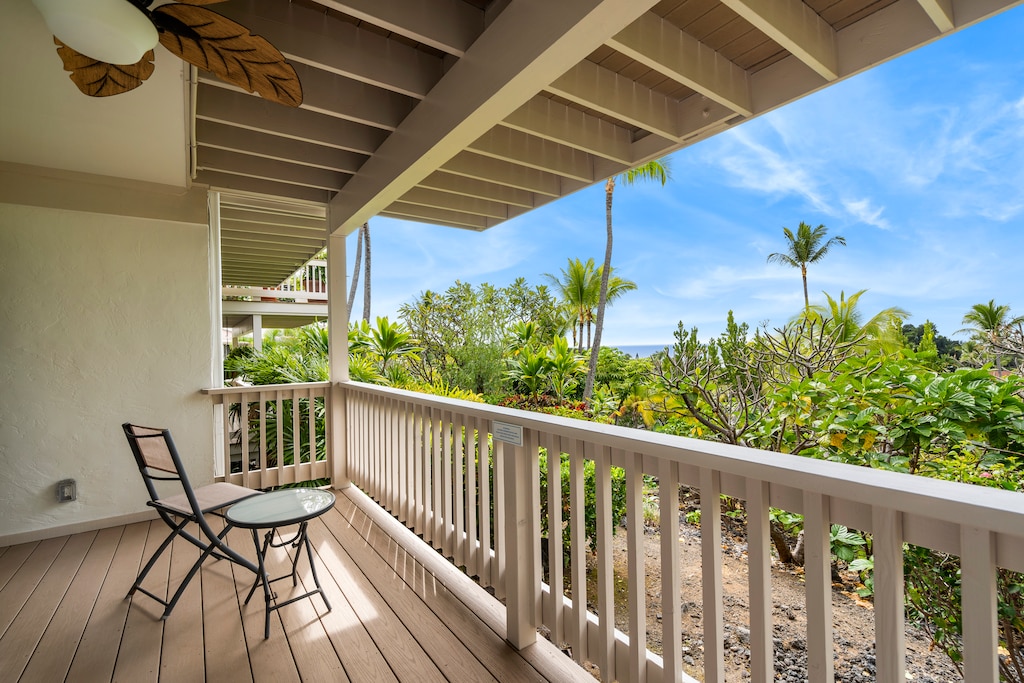 Peaceful lanai with tropical views, ceiling fan, and cozy seating for morning coffee.