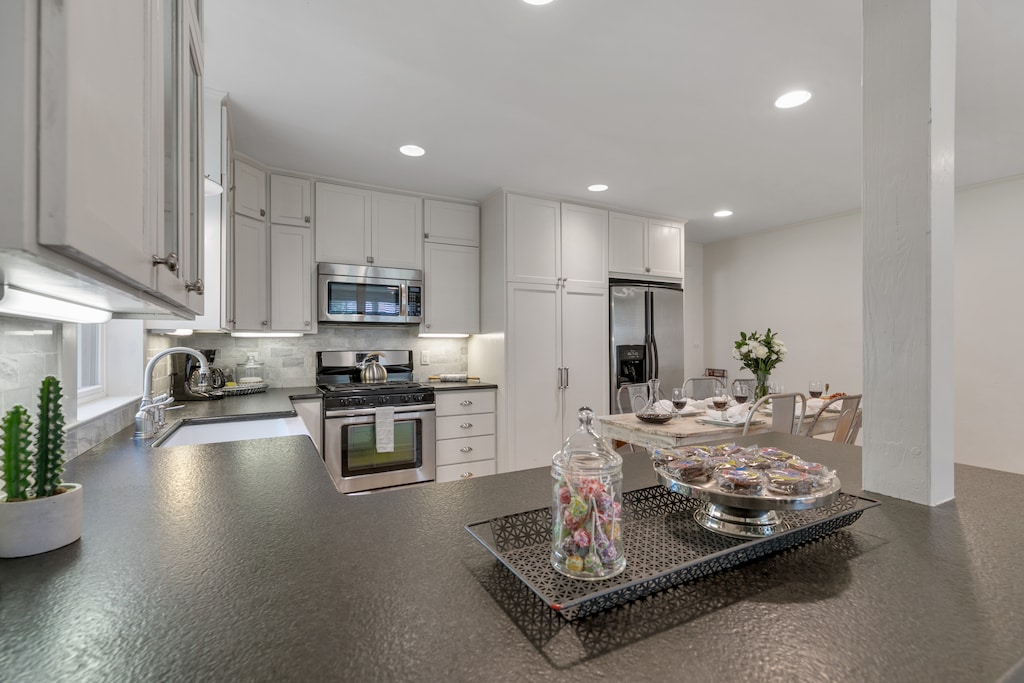 The kitchen is equipped with sleek stainless steel appliances, abundant countertop space, and a charming farmhouse sink for a perfect blend of modern convenience and rustic charm.