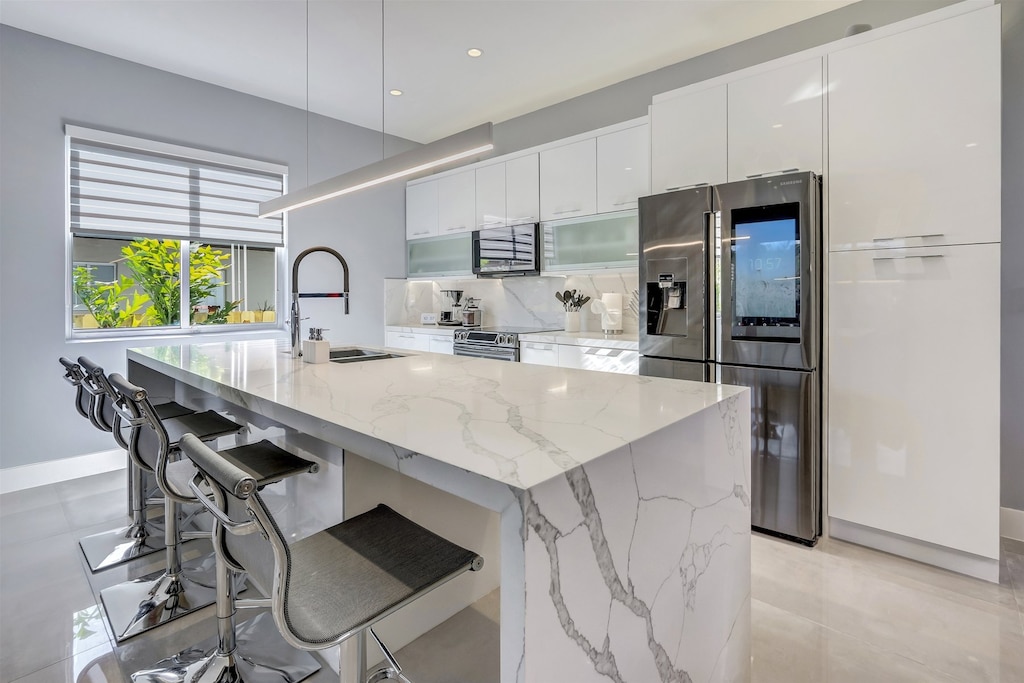 Luxurious kitchen features a white marble, waterfall island -w/ four counter stools-