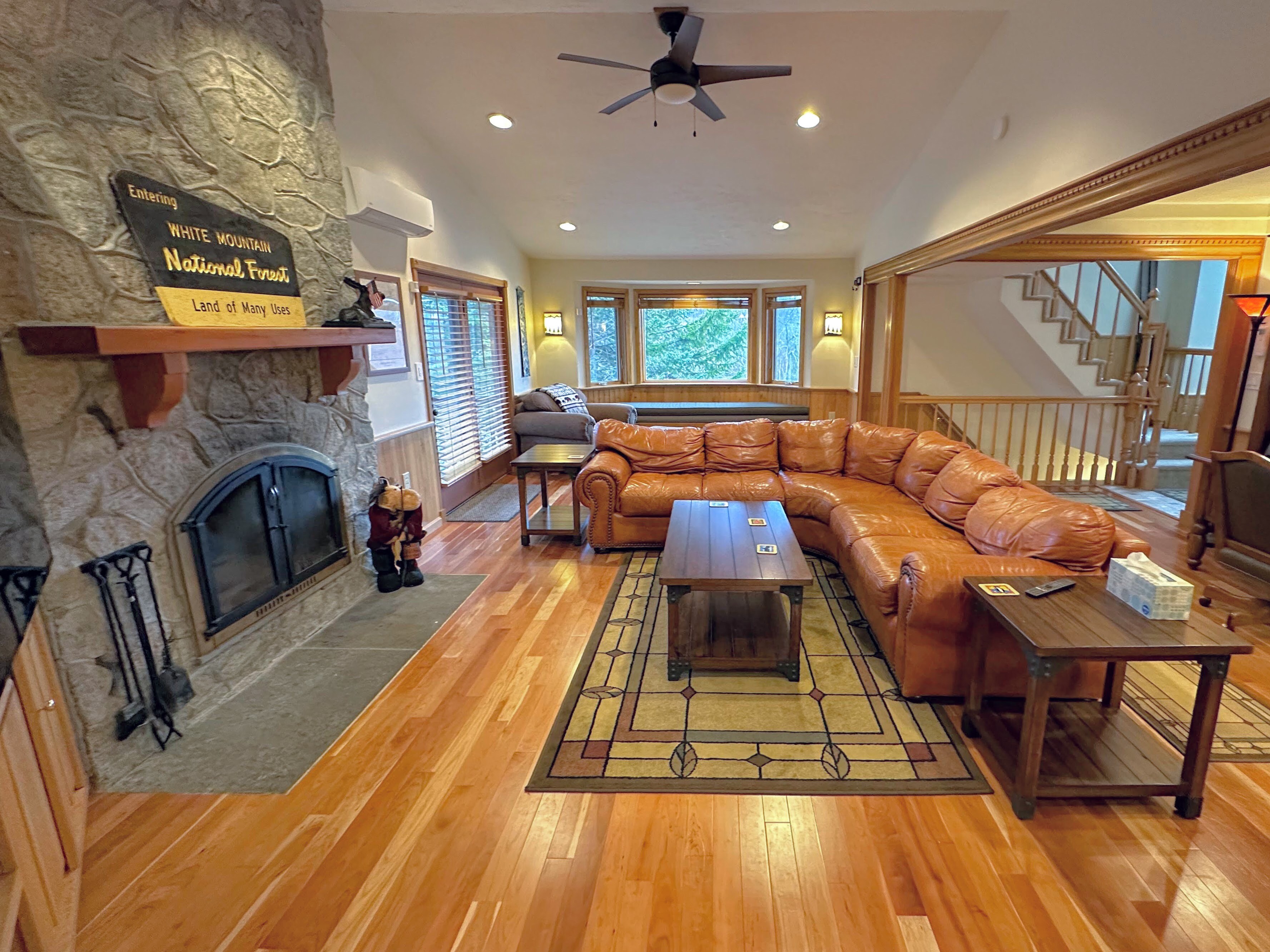 Living area with wood burning fireplace, TV, desk and breakfast bar to kitchen