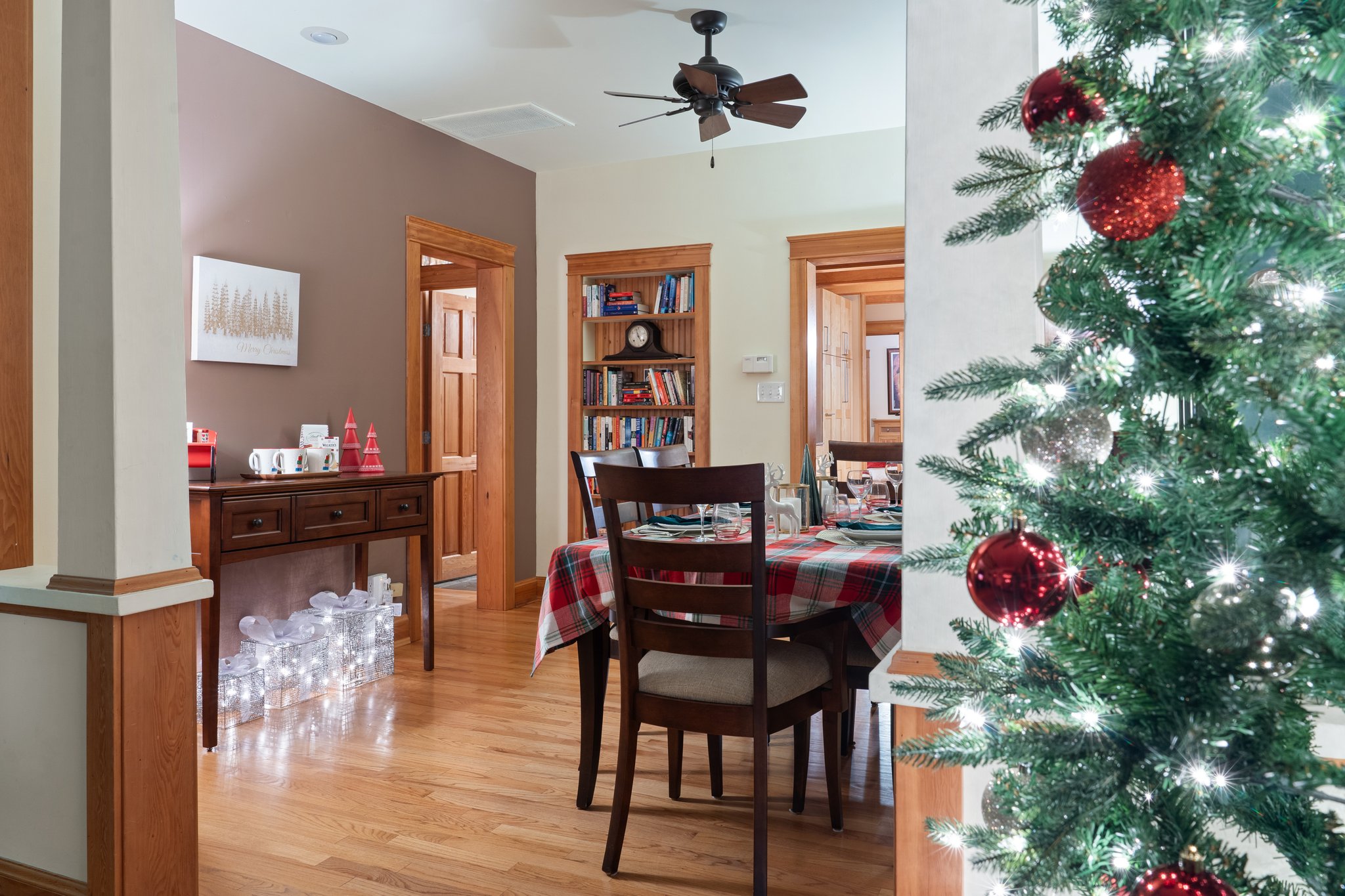 Beautifully decorated Christmas tree standintall in the corner of a welcoming dining room.