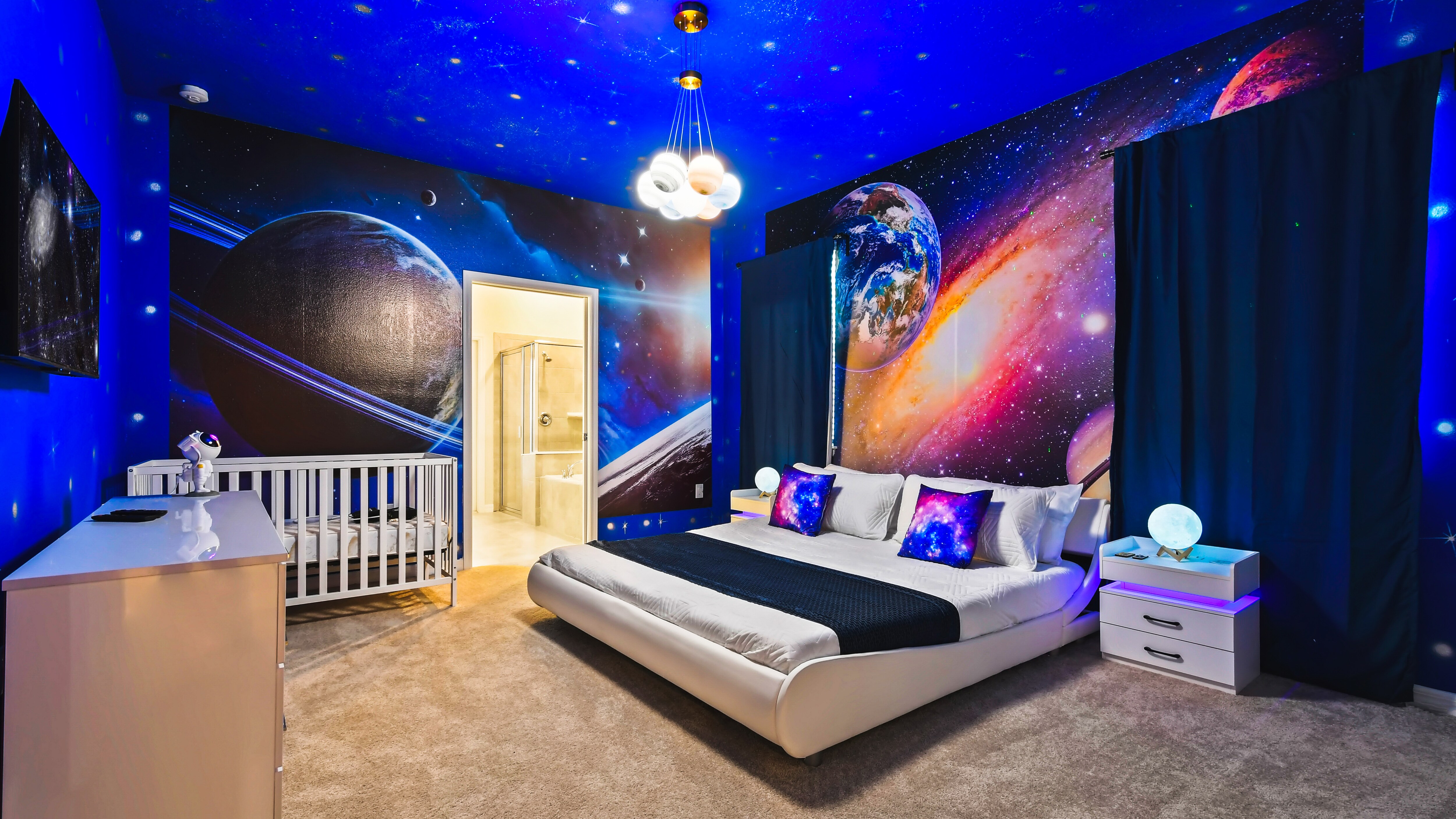 Experience the vastness of the universe in this space-themed bedroom. Complete with cosmic wall murals of planets and stars, the room included a modern bed.