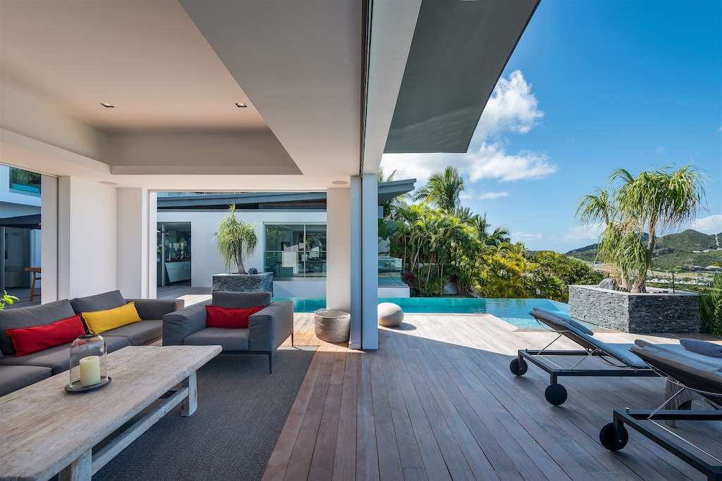 Spacious outdoor living area on the covered patio by the pool, with large and comfy L sofas, facing the panoramic views. Inside lounge area in the great room with the kitchen. 