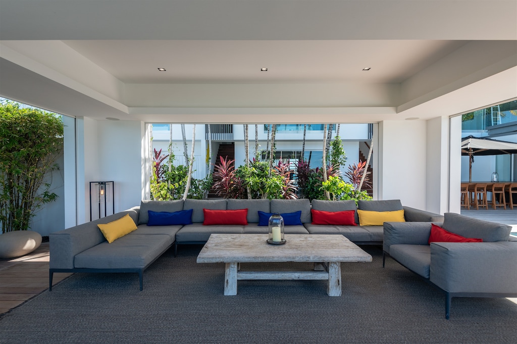 Spacious outdoor living area on the covered patio by the pool, with large and comfy L sofas, facing the panoramic views. Inside lounge area in the great room with the kitchen. 