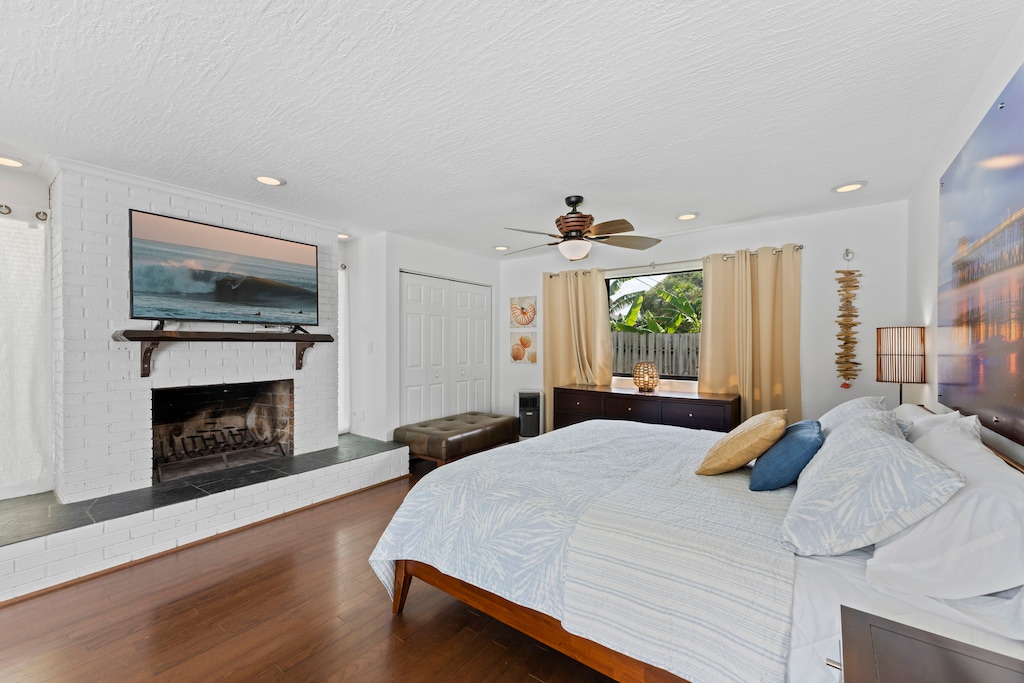 Spacious master bedroom featuring a king bed, flat-screen TV and a cozy fireplace