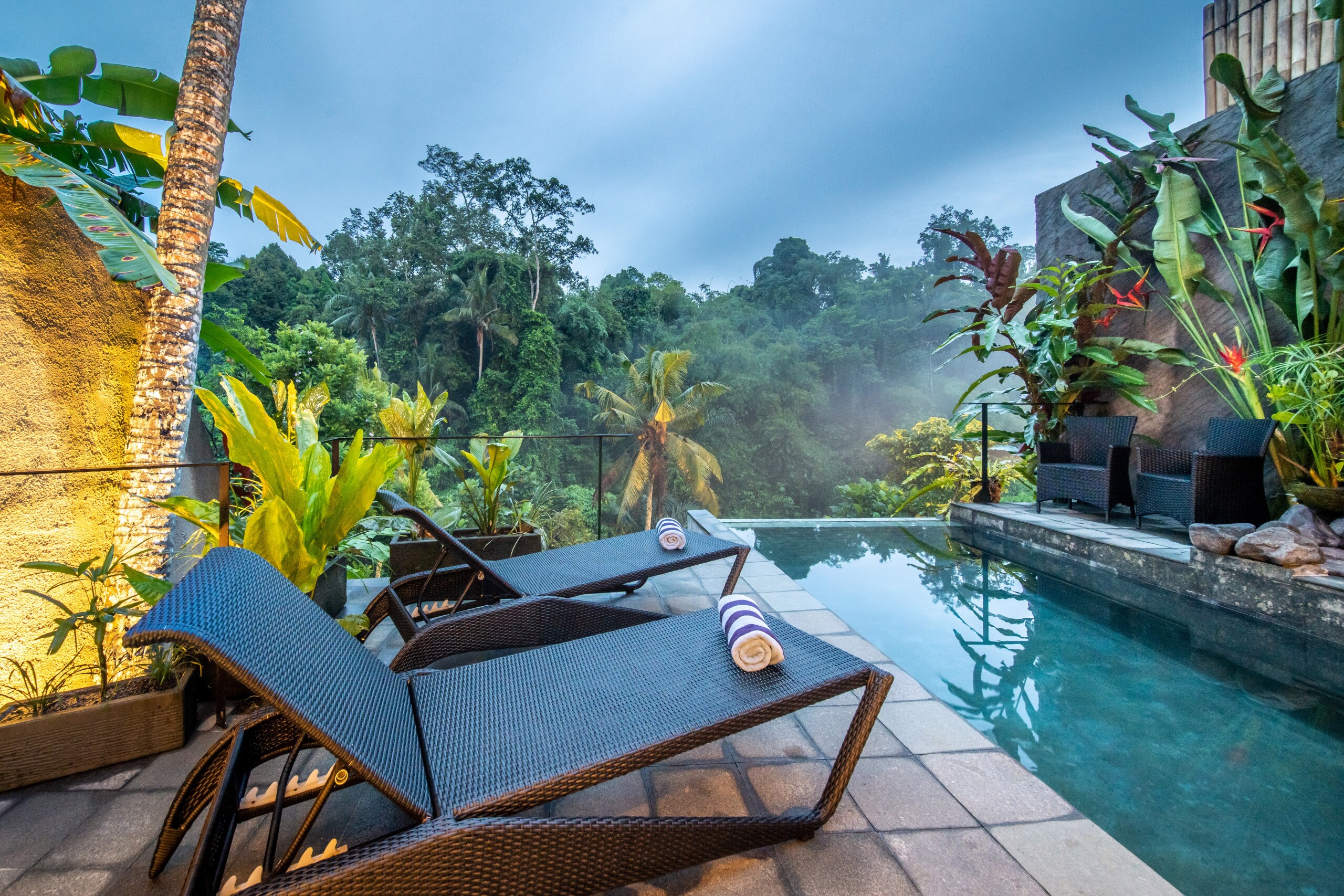 chair lounge in front of a pool with jungle view villa in ubud